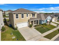 Two-story house with a beige exterior, white garage door, and landscaped front yard at 2011 Chickasaw Blvd, Davenport, FL 33837