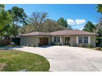 Charming one-story home featuring a spacious driveway, attached garage, and a well-maintained lawn under a clear sky at 33413 Fairway Rd, Leesburg, FL 34788