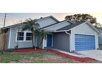 Newly renovated home with gray siding, blue door, and red mulch at 1566 Lawndale Cir, Winter Park, FL 32792