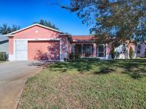 Charming single-story home with a well-maintained lawn and attached two-car garage at 33236 Grand Cypress Way, Leesburg, FL 34748