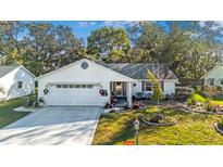 White single-story house with a landscaped yard and attached garage at 1214 Loch Rannoch Ct, Leesburg, FL 34788