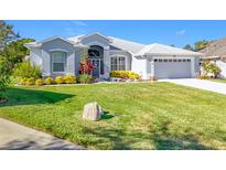 Charming single-story home boasts a well-manicured lawn, vibrant landscaping, and an attached two-car garage at 5401 Water Lily Ct, Leesburg, FL 34748