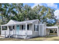Gray house with white trim, front porch, and carport at 1323 Liberty Ave, Mount Dora, FL 32757