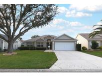 One-story house with a white garage door and landscaped lawn at 1897 Caryle Ln, The Villages, FL 32162