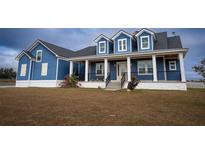 Charming blue two-story home featuring a welcoming front porch with stylish columns and a landscaped front yard at 2437 Bay Lake Loop, Groveland, FL 34736