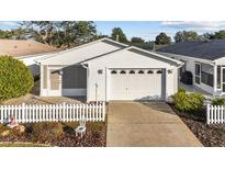 White house with a white picket fence and a two-car garage at 2907 Barboza Dr, The Villages, FL 32162