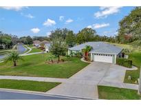 Charming single-story home with a manicured lawn, red front door, and spacious driveway in a serene neighborhood at 8709 Augusta Ct, Clermont, FL 34711