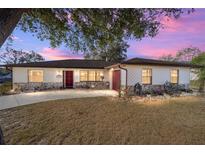 Charming single-story home with stone accents, beautiful landscaping and a well-maintained front yard under colorful sunset at 5640 Se 21St Ln, Ocala, FL 34480