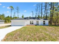Charming single-story home featuring a two-car garage and a well-manicured lawn on a sunny day at 91 Locust Loop, Ocala, FL 34472