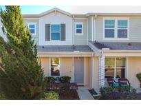 Two-story townhome with gray siding, shutters, and landscaping at 1306 Painted Bunting Ave, Oakland, FL 34787