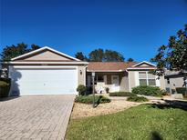 Tan one-story house with a two-car garage and landscaped yard at 16914 Se 96Th Chapelwood Cir, The Villages, FL 32162