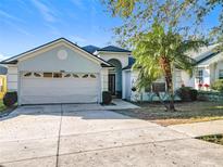 House exterior featuring a two-car garage and landscaped yard at 10424 Stonepark Dr, Leesburg, FL 34788