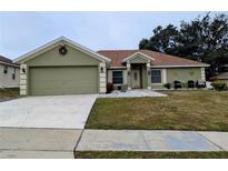 Green house with a two-car garage and well-maintained lawn at 1315 Willow Wind Dr, Clermont, FL 34711