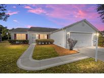 White house with a two-car garage and manicured lawn at dusk at 1509 Yucatan Way, The Villages, FL 32159
