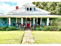 Charming teal house with a wrap-around porch and landscaped yard at 176 S Trowell Ave, Umatilla, FL 32784