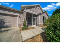 The house features a screened front entry, an attached garage, and manicured landscaping at 1828 Feliciana Ter, The Villages, FL 32162