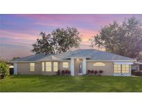 Tan house with gray roof, white trim, and landscaping; dusk photo at 5622 King James Ave, Leesburg, FL 34748