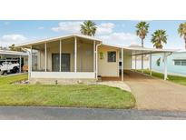 Charming single-story home with a screened-in porch, carport, manicured lawn, and palm trees at 12 Hilly Way, Fruitland Park, FL 34731