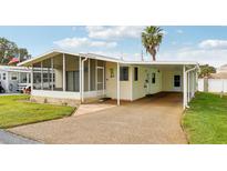 Charming single story home featuring an attached carport, a screened in porch, and a well-maintained lawn at 12 Hilly Way, Fruitland Park, FL 34731