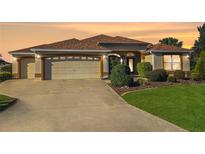 Charming one-story home featuring a two-car garage and a beautifully landscaped front yard at sunset at 17716 Se 85Th Ellerbe Ave, The Villages, FL 32162