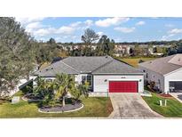 Single-story home with red garage door and landscaping at 3839 Manor Oaks Ct, Leesburg, FL 34748