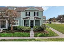 Two-story townhome with light teal exterior, screened porch, and landscaping at 565 Juniper Springs Dr, Groveland, FL 34736