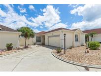 Charming single-story home with a well-manicured lawn, a concrete driveway, and an attached garage at 1330 Lajolla Cir, The Villages, FL 32159