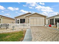 Cute one-story home with a white picket fence and a paved driveway at 2428 Kingstree Pl, The Villages, FL 32162