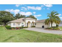 Single-story home with a two-car garage and well-manicured lawn at 5072 Greens Dr, Lady Lake, FL 32159