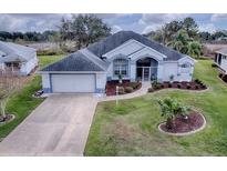 Single-story home with gray roof, white walls, and landscaped yard at 5626 Squires Dr, Leesburg, FL 34748