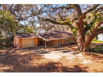 Charming single-story home featuring a detached garage and a spacious front yard shaded by mature oak trees at 6100 Windmill Rd, Leesburg, FL 34748