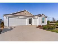 White house with two-car garage and landscaped yard at 6182 Dingman Way, The Villages, FL 32163