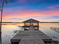 Sunset view of a lakefront dock with a covered sitting area at 8415 Colony Barn Rd, Clermont, FL 34714