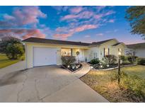 Inviting yellow house with landscaped yard and driveway at 934 Orchid St, The Villages, FL 32159