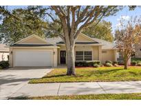 Tan one-story house with a white garage door and landscaping at 979 Princeton Dr, Clermont, FL 34711