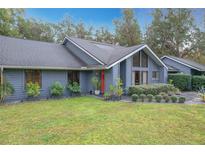 Gray house with landscaped yard, red door, and unique architectural details at 1701 Cedar Stone Ct, Lake Mary, FL 32746