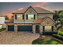 Two-story house with stone accents and a three-car garage at 17889 Gourd Neck Loop, Winter Garden, FL 34787