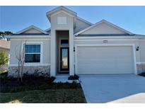 One-story home with light gray siding, stone accents, and a two-car garage at 2022 Wallingford Loop, Mount Dora, FL 32757