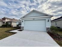 House exterior featuring a light blue color scheme, a two-car garage, and a stone facade at 2046 Wallingford Loop, Mount Dora, FL 32757