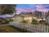 Charming home with a white picket fence, beautiful landscaping, and an inviting patio area at 2821 Barboza Dr, The Villages, FL 32162