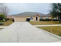 Tan house with a two-car garage and landscaped lawn at 3236 White Blossom Ln, Clermont, FL 34711