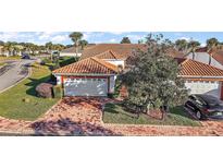 Brick-paved driveway leads to a charming villa with a terracotta tile roof and a two-car garage at 5046 Harbour Dr, Oxford, FL 34484