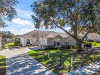 Single-story house with attached garage, driveway and mature landscaping at 6220 Topsail Rd, Lady Lake, FL 32159