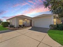 Tan house with white garage door and landscaping at 6220 Topsail Rd, Lady Lake, FL 32159