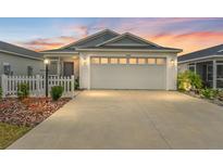 White house with gray roof, attached garage, and landscaped front yard at 7189 Denver Ave, The Villages, FL 34762