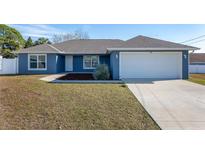 Newly constructed home with a blue exterior, two car garage, and a well-manicured lawn at 105 Juniper Run, Ocala, FL 34480