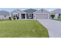 Gray one-story house with two-car garage, landscaping, and a large front yard at 11414 Roma Rd, Oxford, FL 34484