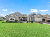 Gray two-story house with landscaped lawn and two-car garage at 12413 Se 176Th Loop, Summerfield, FL 34491