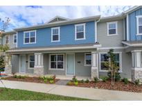 Two-story townhome with blue and gray siding, stone accents, and a front porch at 13241 Peaceful Melody Dr, Winter Garden, FL 34787