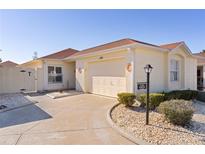 Front view of charming villa with attached garage and landscaped yard at 1341 Lajolla Cir, The Villages, FL 32159